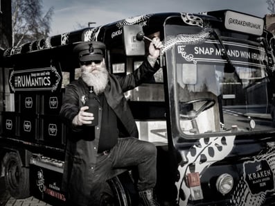 A black and white photo of the Kraken electric milk float, with the driver posing.