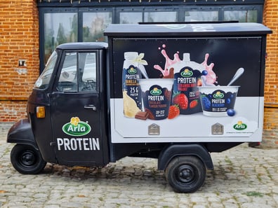 The black Arla Piaggio Ape, advertising protein food and drink.