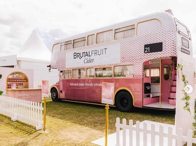 The Brutal Fruit Cider Routemaster bus parked near a tent at a festival.