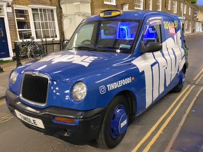 The front of the Tindle Foods taxi rental, driving along a road.