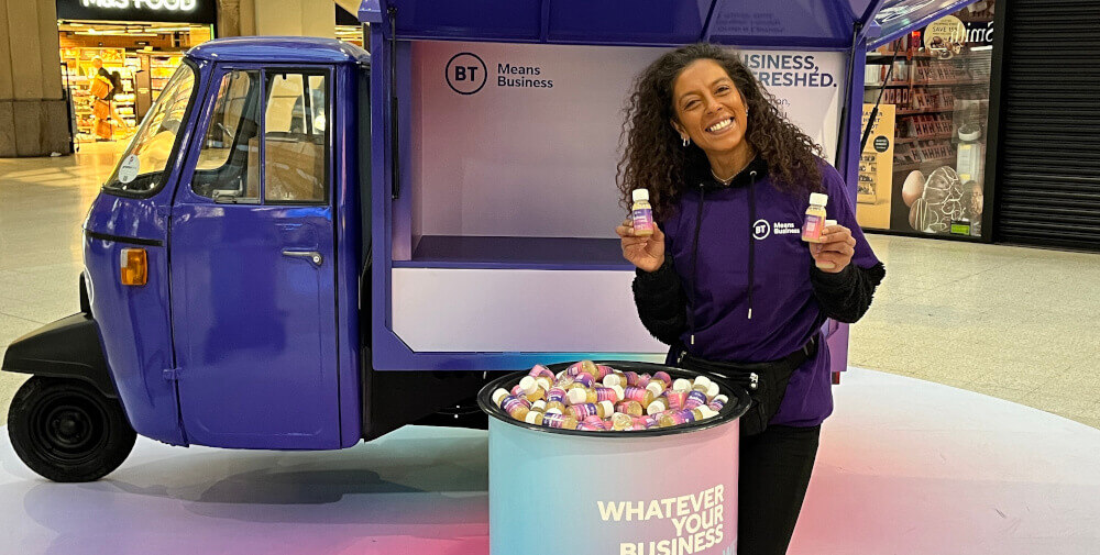 A BT brand ambassador hands out samples in front of a promotional Piaggio Ape.