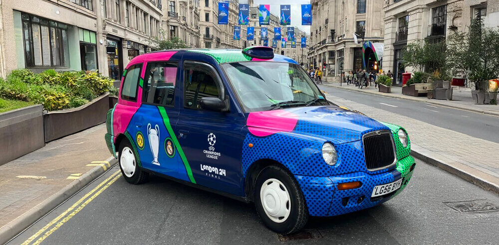 Champions league Taxi, branded in different colours on a city street.