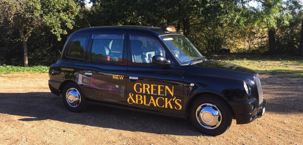 An image of the classic TX series London cab, branded for Green & Blacks.