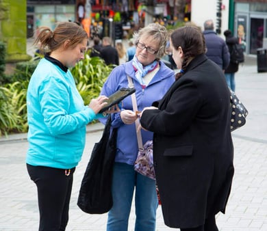 A woman getting sign-ups at a brand experience event.