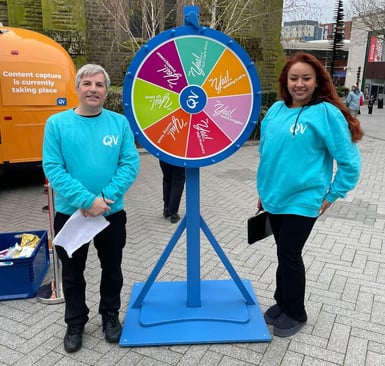 QV Skincare brand ambassadors stand in front of a 'spin the wheel' game.