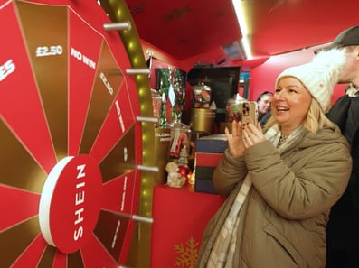 A guest plays a spin wheel game in the SHEIN Christmas bus