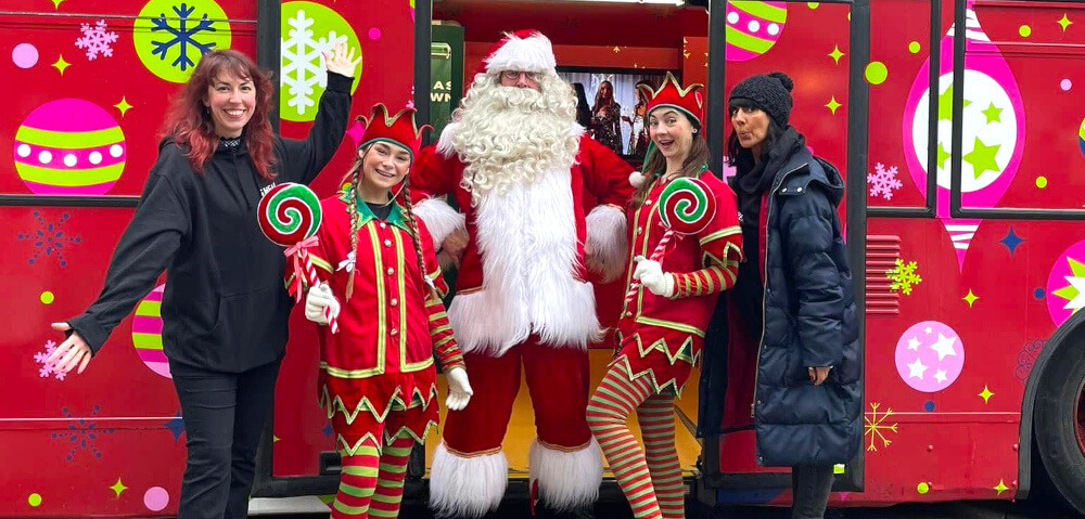 Santa and elves pose outside the red SHEIN festive campaign bus