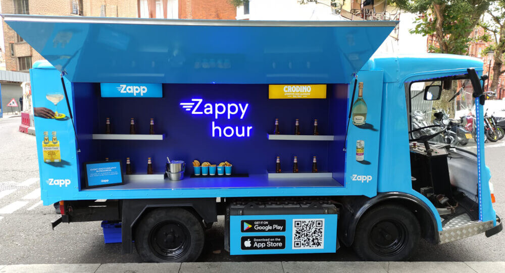 The Zapp electric milk float, with a neon sign and open display.