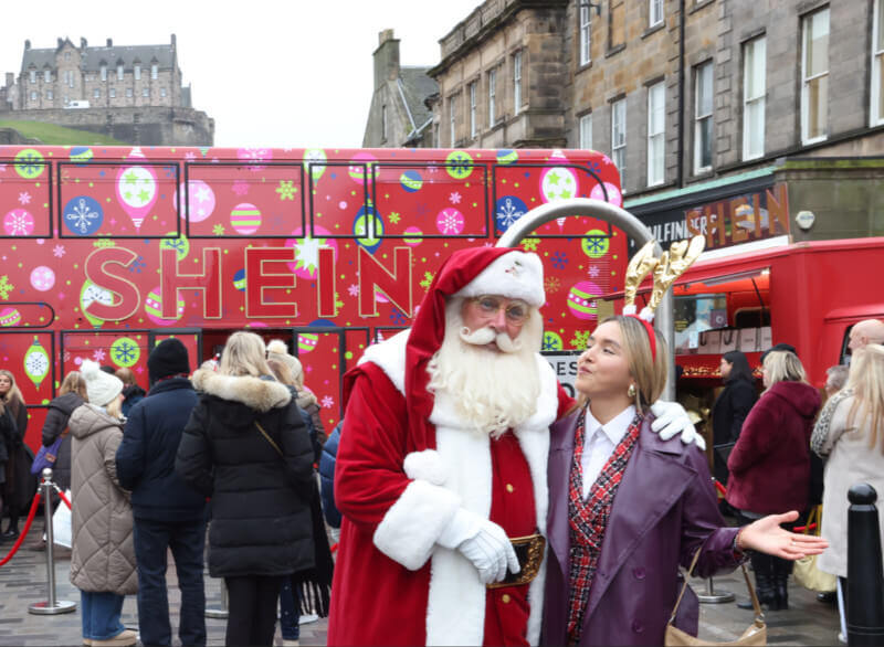 SHEIN's Festive Campaign: An image of Santa with a guest in front of the red SHEIN bus.